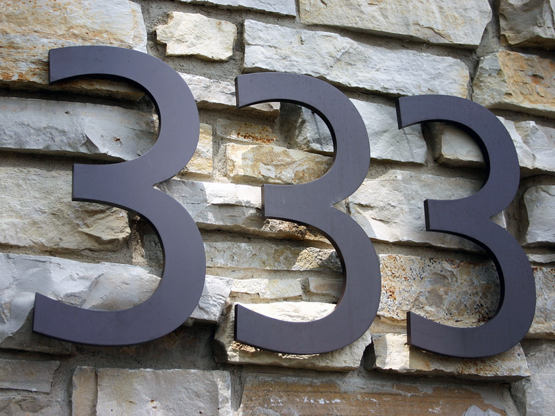 Bronze address numbers against a brick background