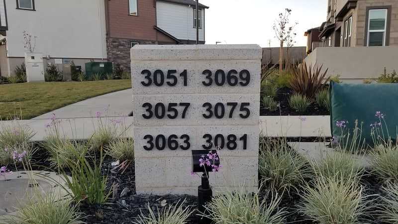 Black anodized aluminum numbers on a white brick background