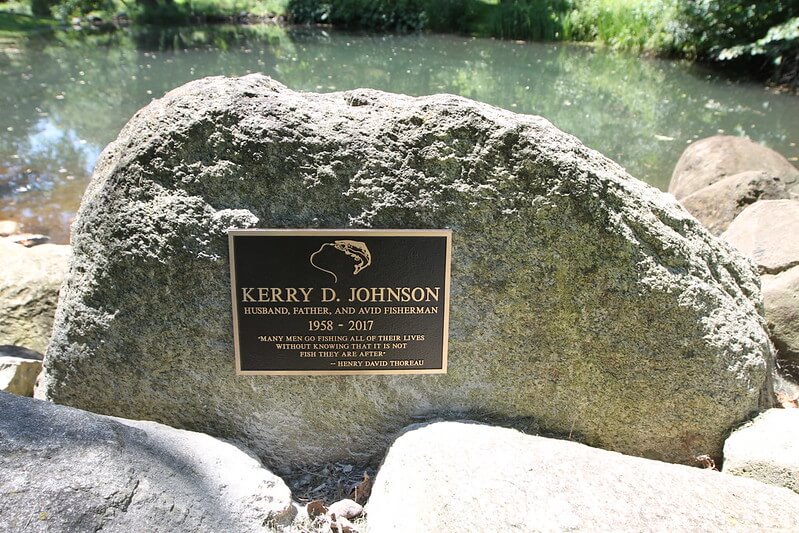 A plaque installed near a lake in memory of an avid fisherman by his family